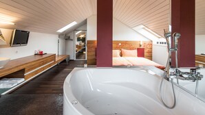 Une salle de bain moderne avec une grande baignoire, un meuble-lavabo en bois et un miroir.