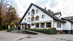 Un bâtiment blanc avec un toit en pente, un balcon et une enseigne indiquant « hôtel ».