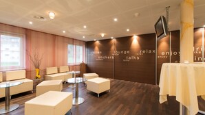 Un espace de détente moderne, doté de sièges et de tables, d’un grand écran et d’un mur orné de phrases inspirantes.