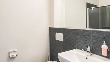 A modern bathroom with a white toilet, a sink, and a mirror.