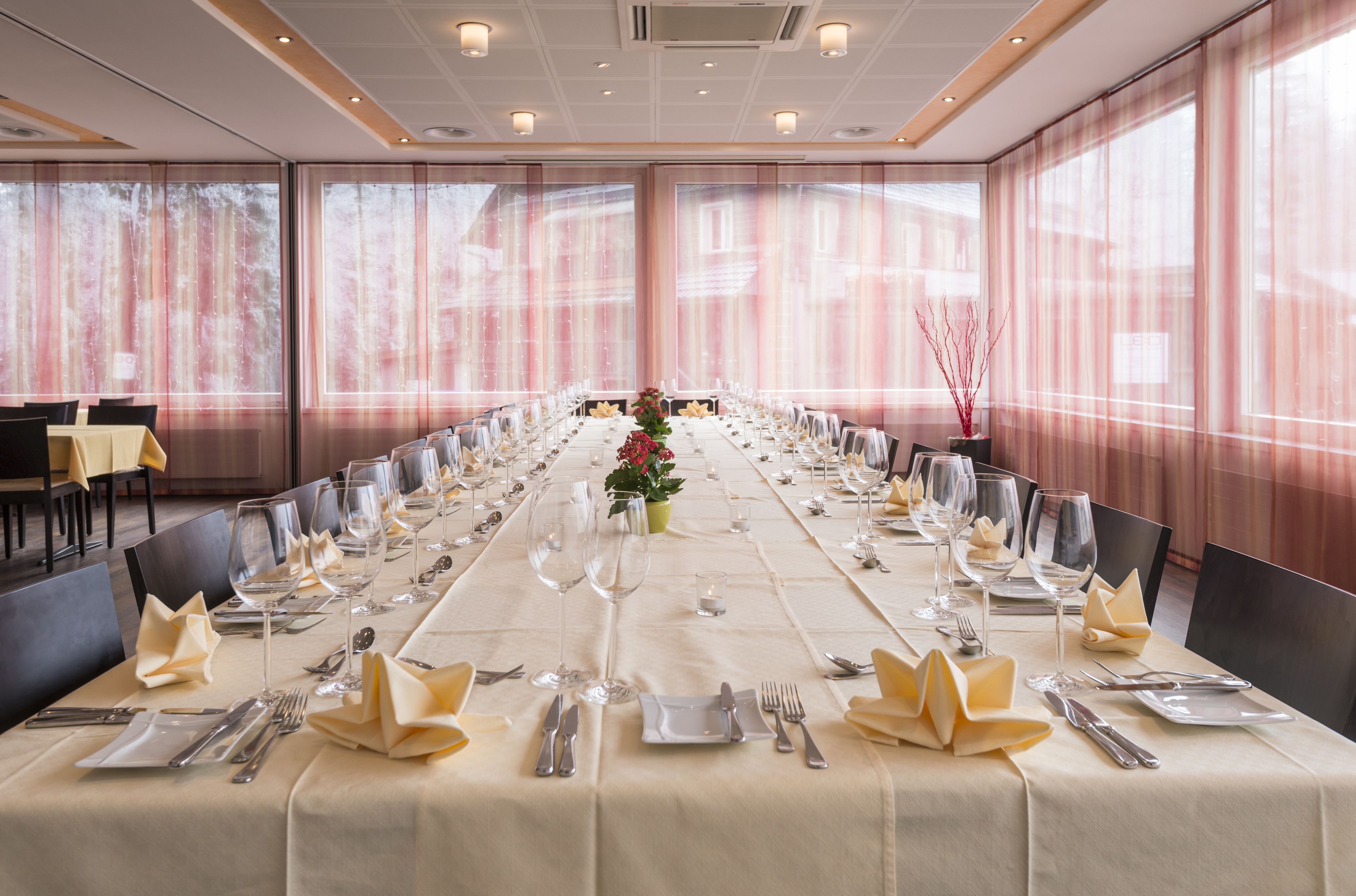 A long banquet table set for a formal event, with chairs aligned on both sides.