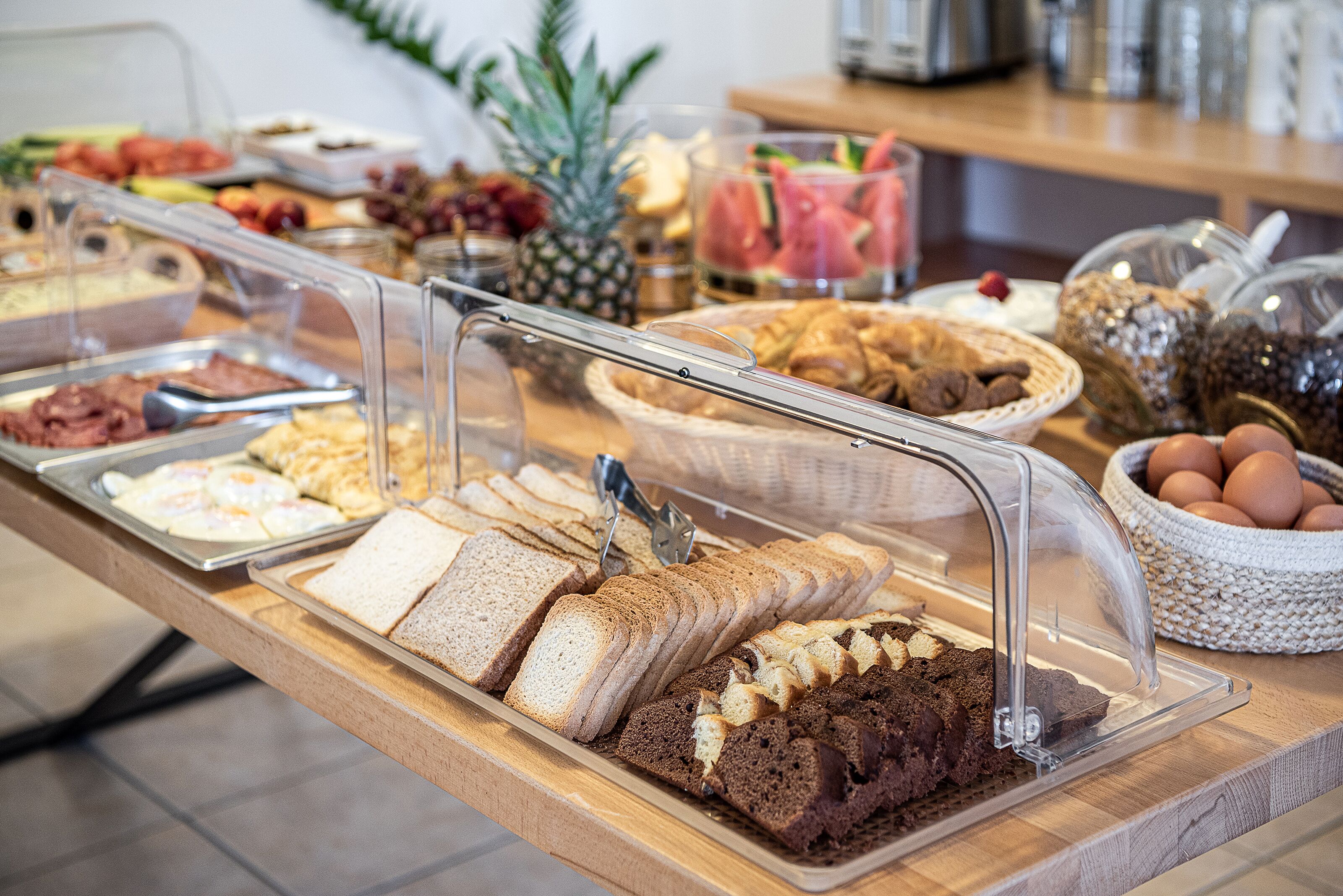 A buffet with various food items including bread, pastries, and fruits.