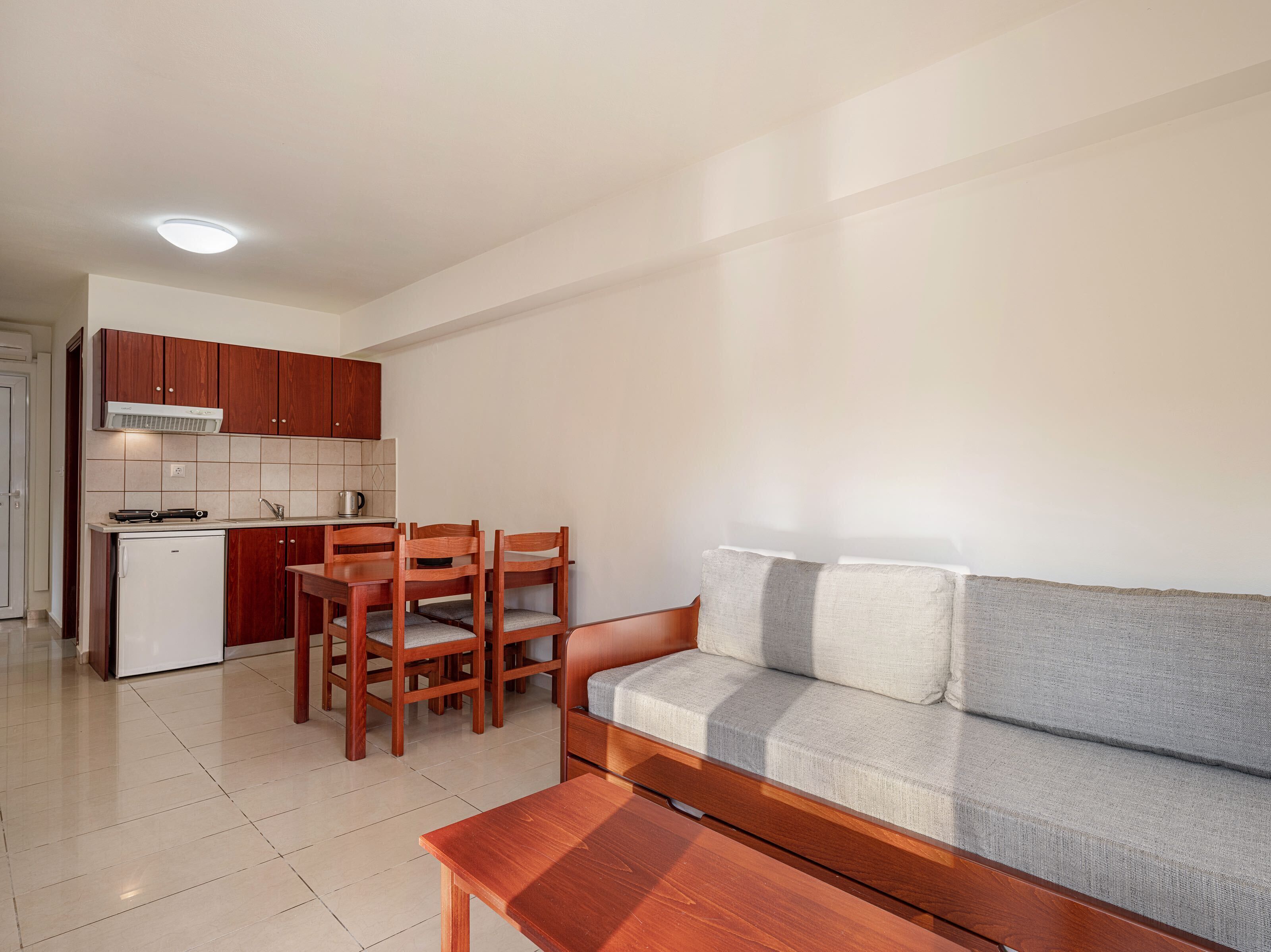 A compact living space with a kitchenette, a sofa, and a dining area.