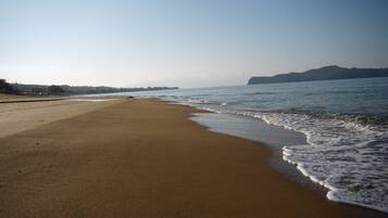 Enjoy a serene beach experience with uninterrupted views of the ocean and surrounding hills.