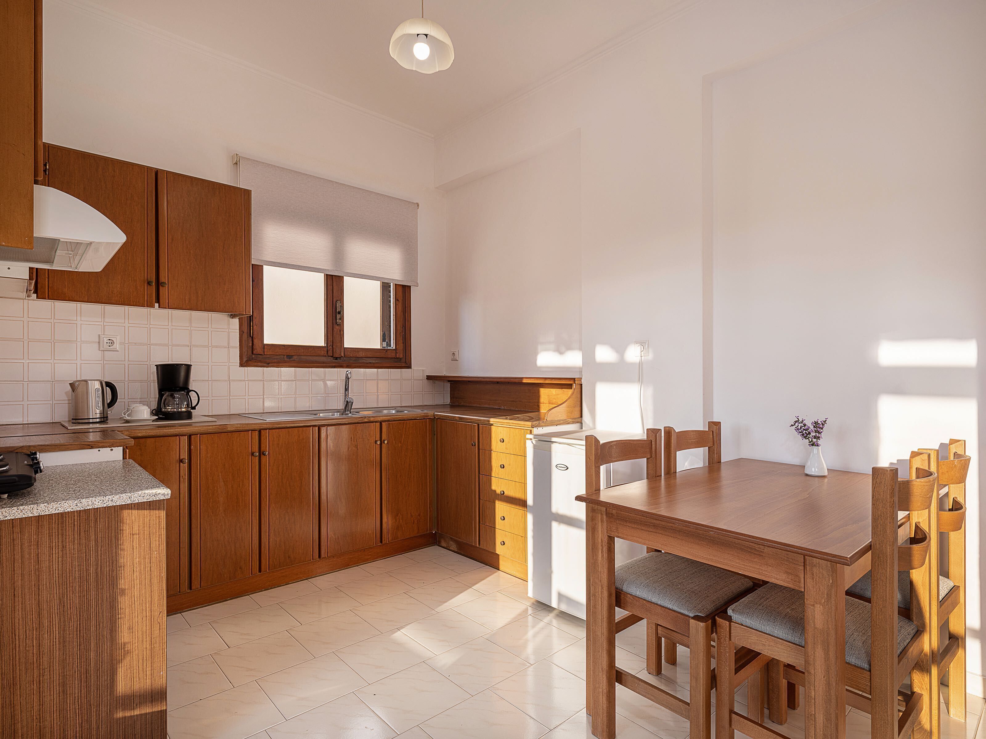 A modern kitchen with wooden cabinets, a built-in dishwasher, and a dining area with a wooden table and chairs.