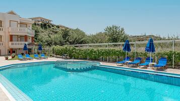 Alberca al aire libre, sombrillas en la alberca y camastros