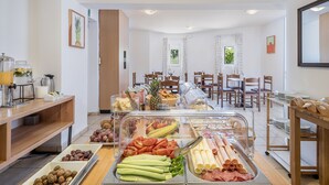 A buffet with various food items and a seating area with tables and chairs. - Artemis Apartments (Chania)
