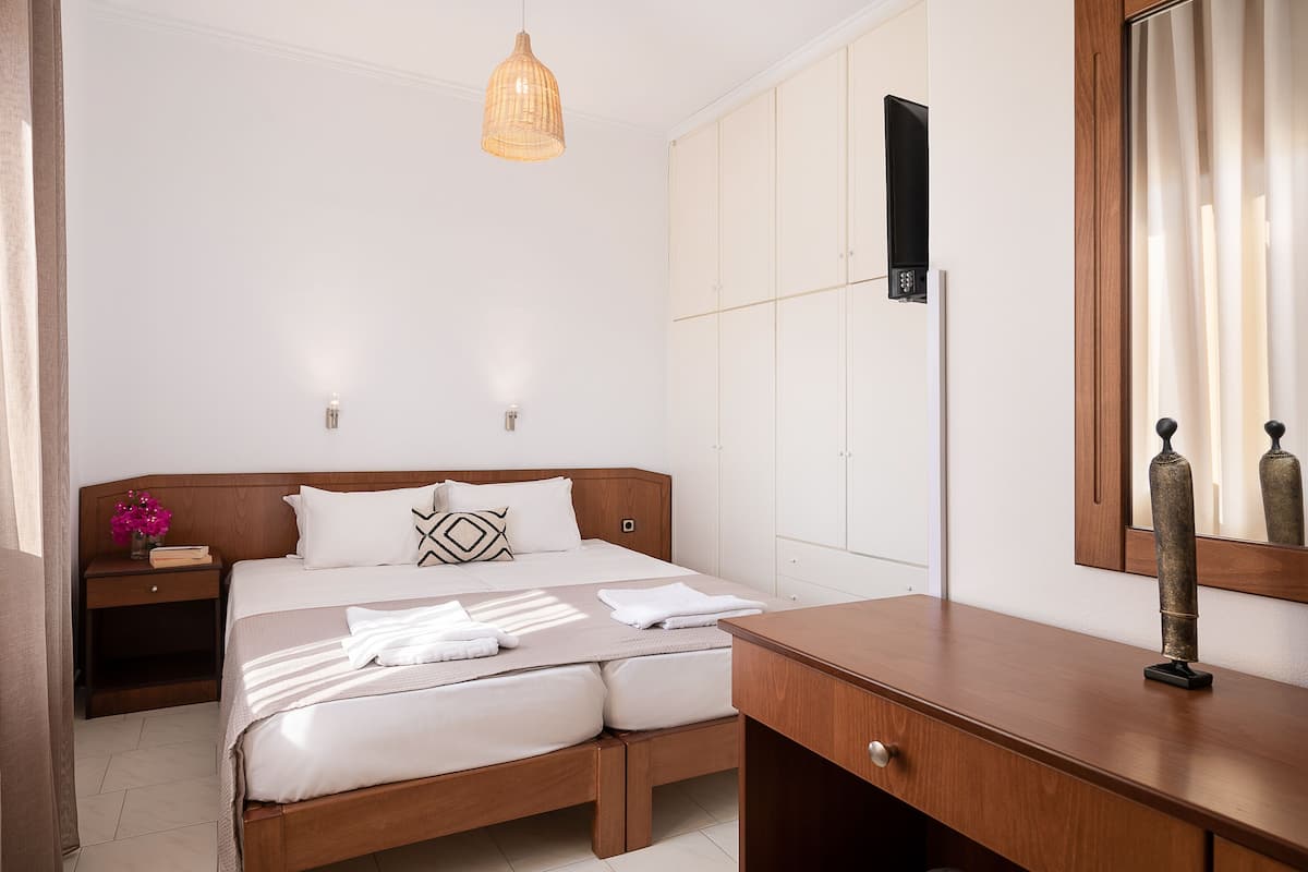 A neatly arranged bedroom with a wooden bed, bedside tables, a dresser, and a large mirror.