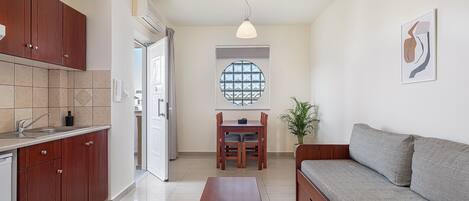 Una cocina moderna con armarios de madera, un comedor con mesa y sillas, y una sala de estar con sofá.