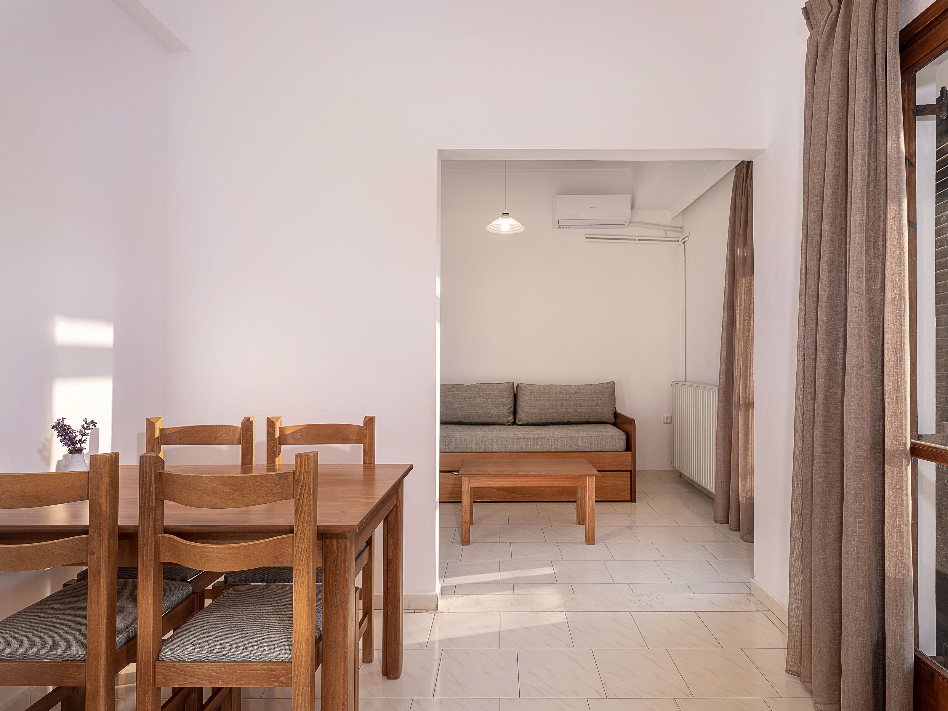 A dining area with wooden chairs and a table, a sofa, and a radiator.