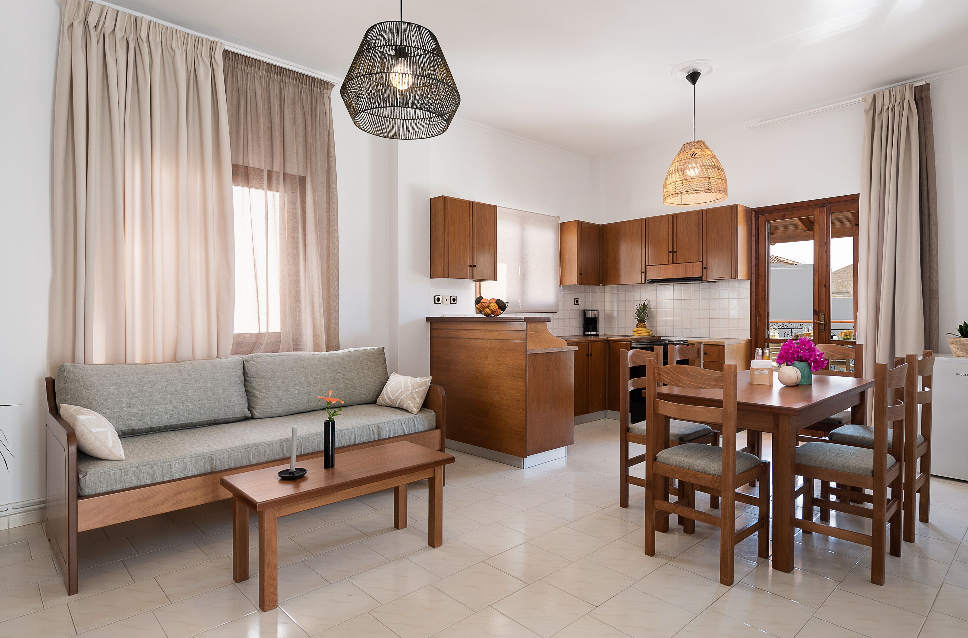 Una cocina moderna con armarios de madera, una mesa de comedor con sillas, un sofá, una mesa baja y luminarias colgantes.