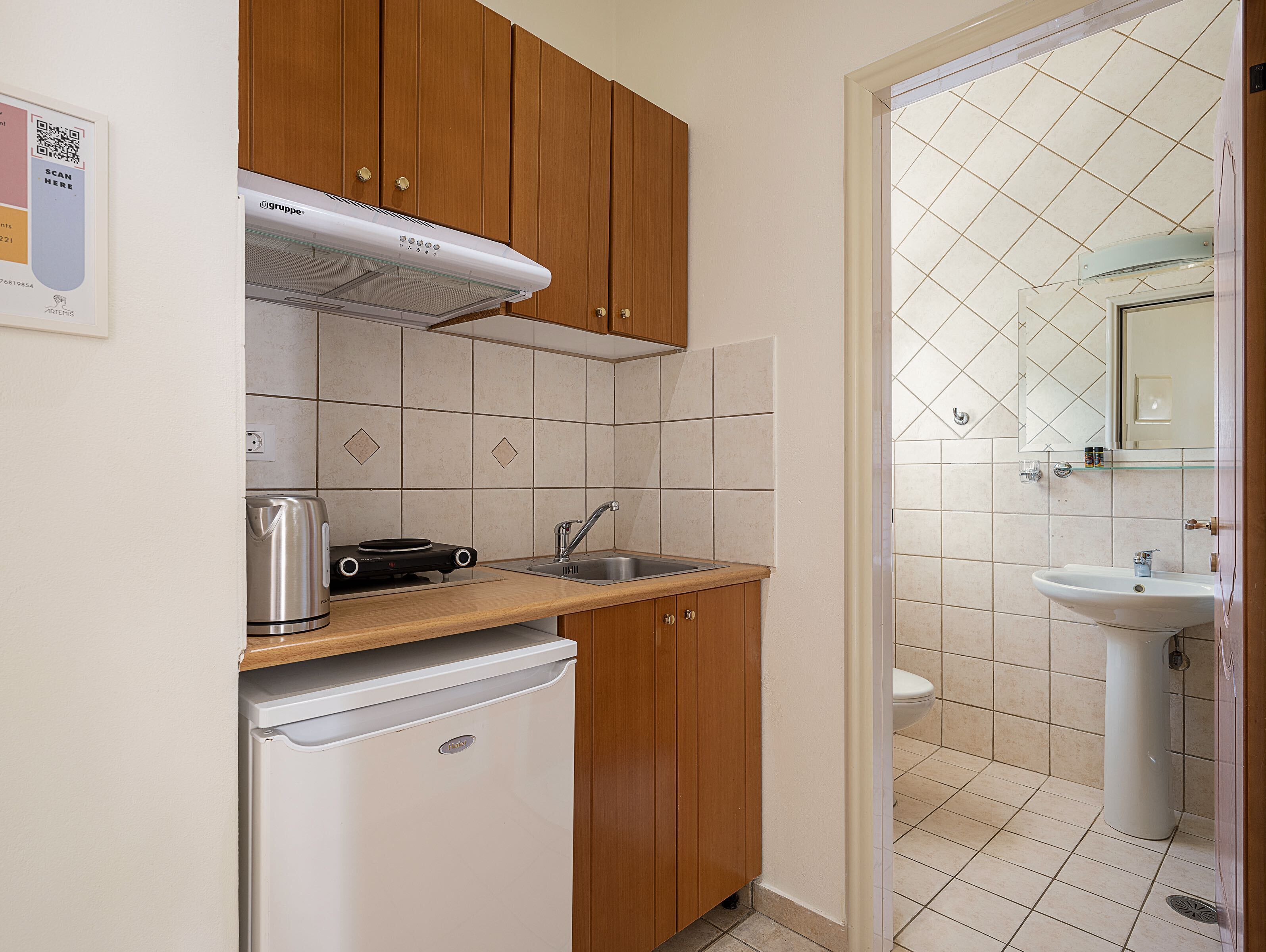 Een compacte keuken met houten kastjes, een inbouwoven, een spoelbak en een kleine koelkast.