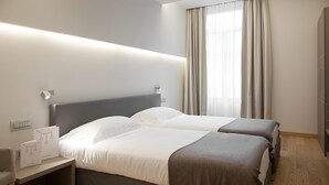 A modern hotel room with two beds, a bedside table, and a large window with curtains. - Hotel di Varese (Varese)