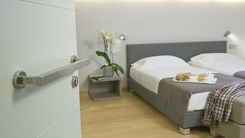 A modern hotel room with a bed, bedside table, and a small plant.