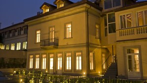 A multi-story building with illuminated windows and a balcony, featuring a staircase leading to the upper floors. - Hotel di Varese (Varese)