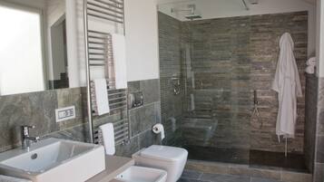 Un baño moderno con un espejo grande, un lavamanos, un inodoro y una zona de ducha con mampara de vidrio.