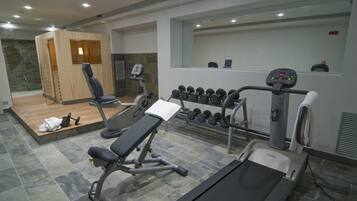 Un gimnasio moderno con una variedad de equipos, incluyendo mancuernas, una prensa de banca y una cinta de correr.