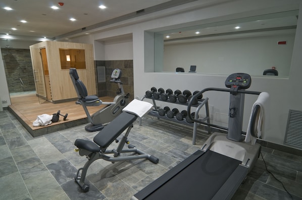 A modern gym with a variety of equipment including dumbbells, a bench press, and a treadmill.