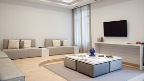 A modern living room with a sofa, a coffee table, and a TV mounted on the wall. - Hotel di Varese (Varese)