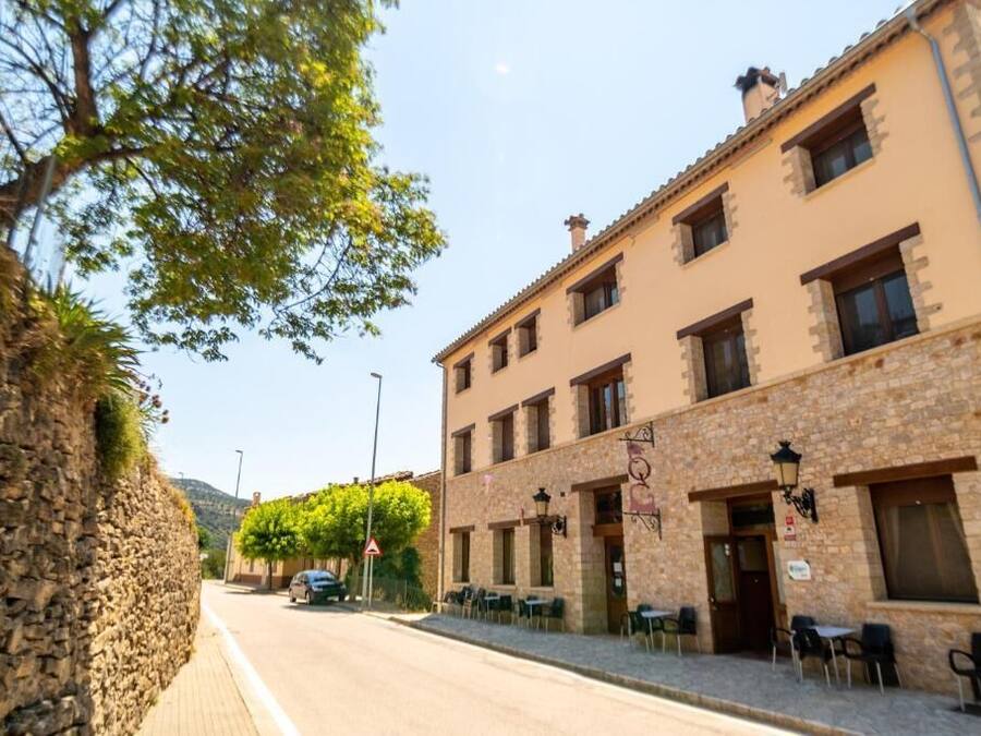 A street view of a building with a stone facade, multiple windows, and outdoor seating area.