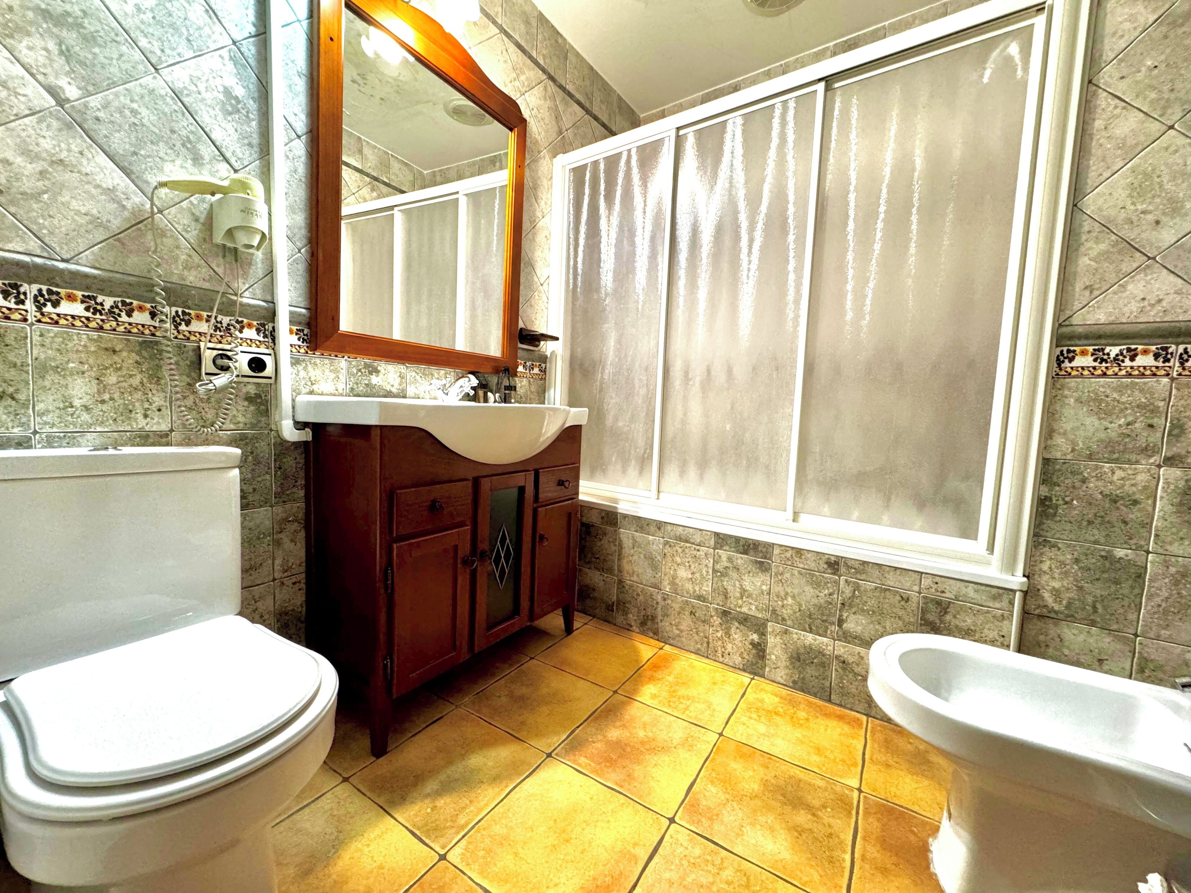 Een badkamer met toilet, wastafel en bad.