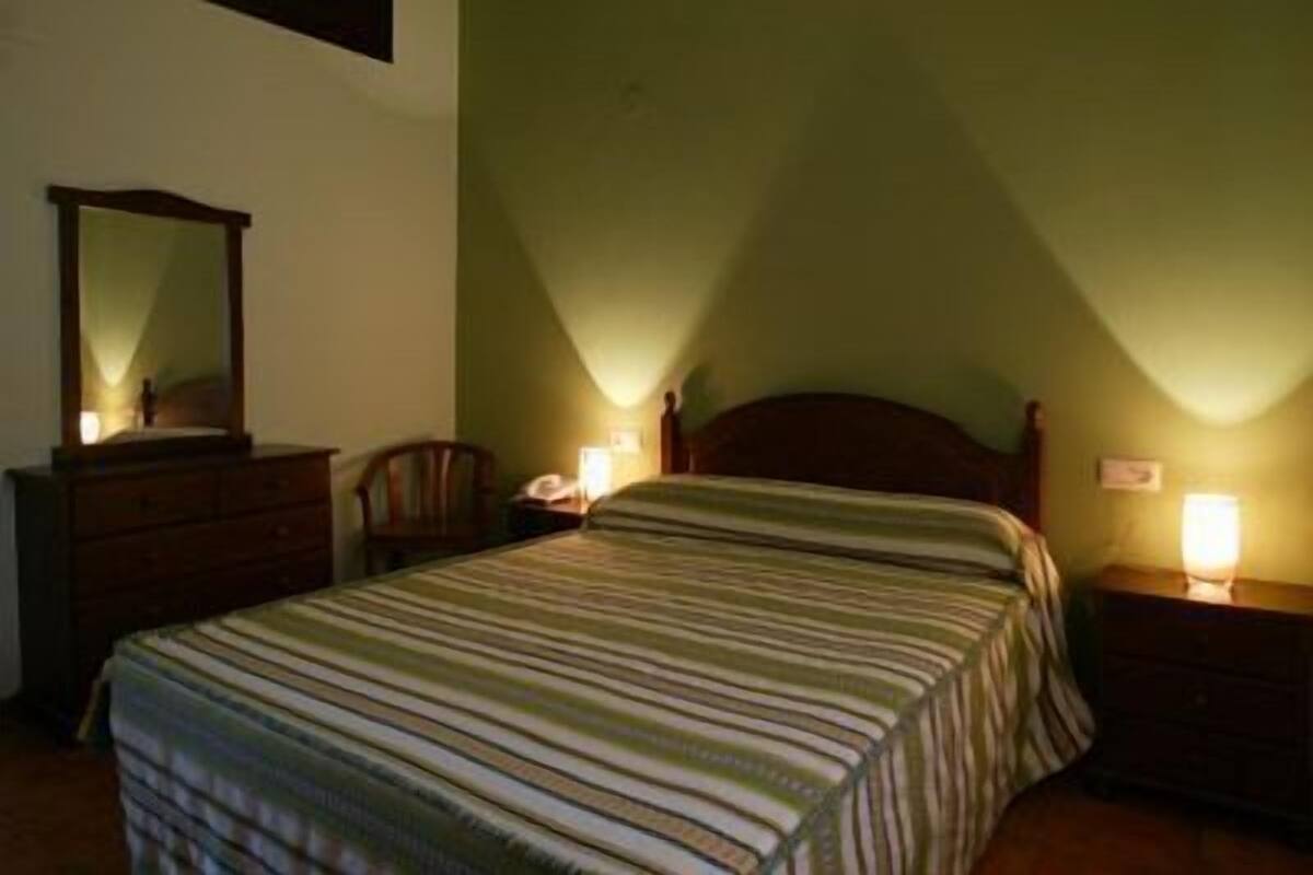 Une chambre à coucher avec un lit, une commode, une chaise et deux lampes de chevet.