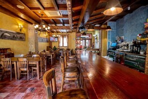 A bar area with wooden tables and chairs, a long counter, and a barista station.
