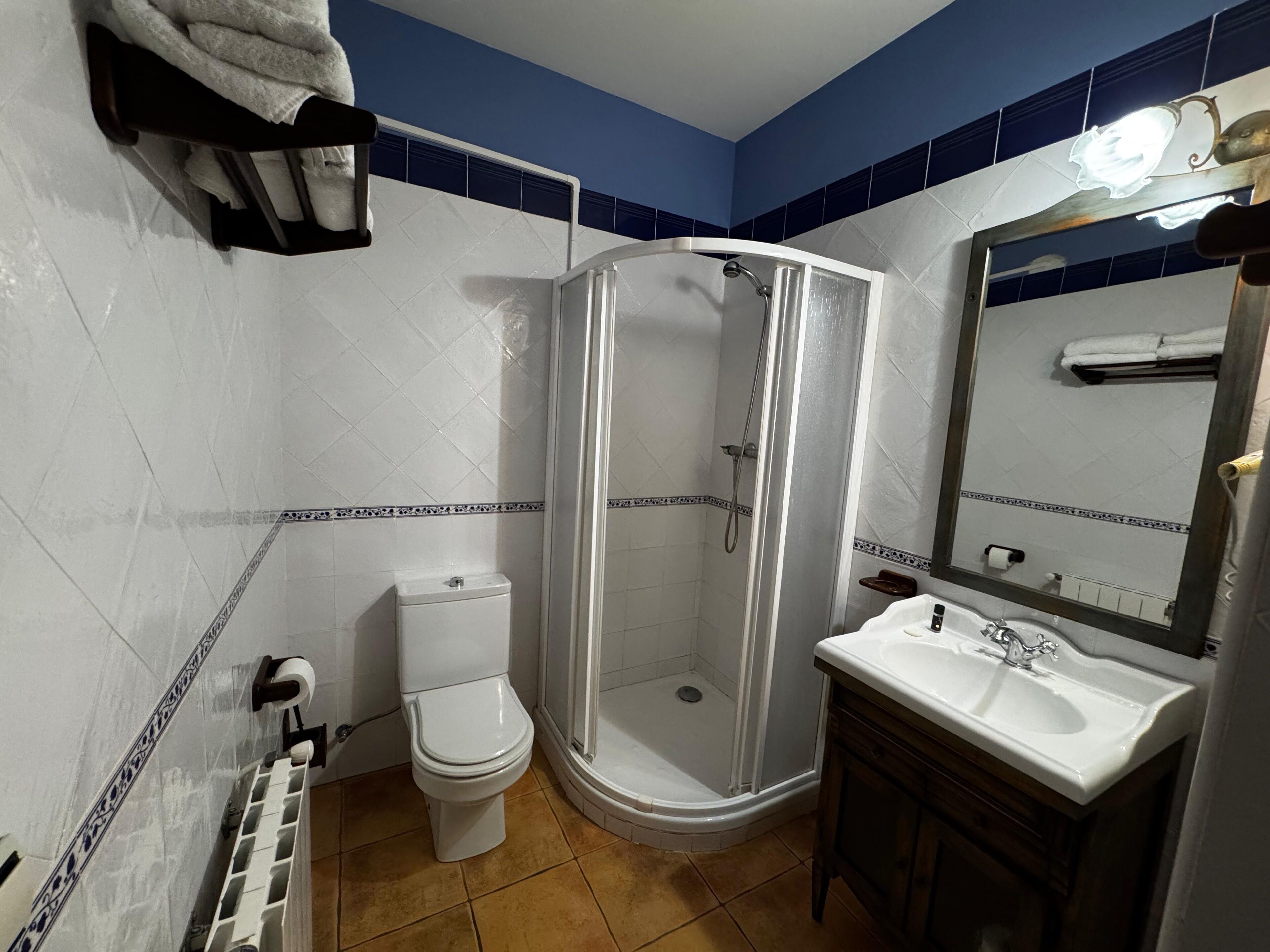 Un baño con inodoro, cabina de ducha, lavamanos y espejo.