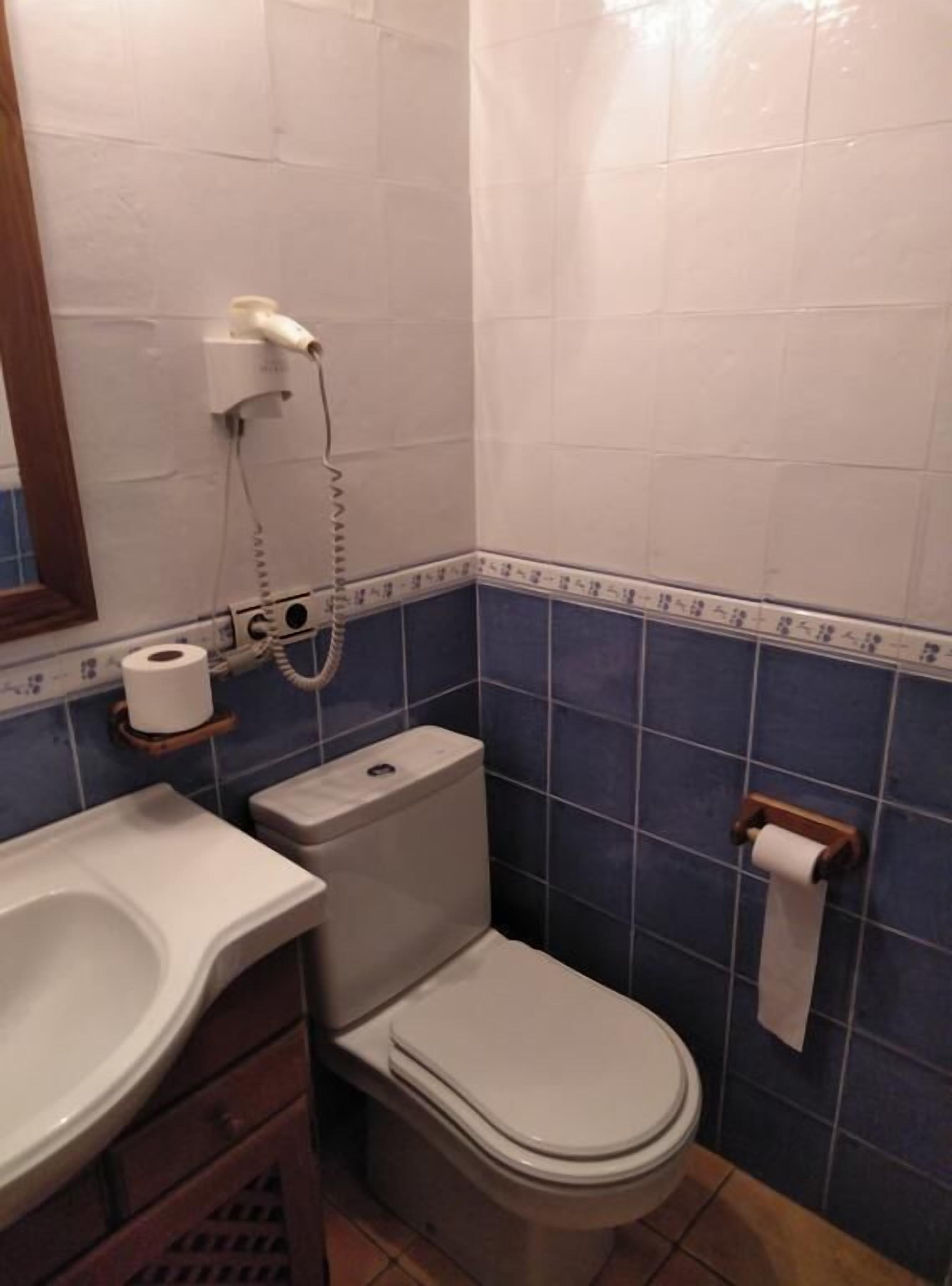 Ein Badezimmer mit Toilette, Waschbecken und Papierhandtuchspender.