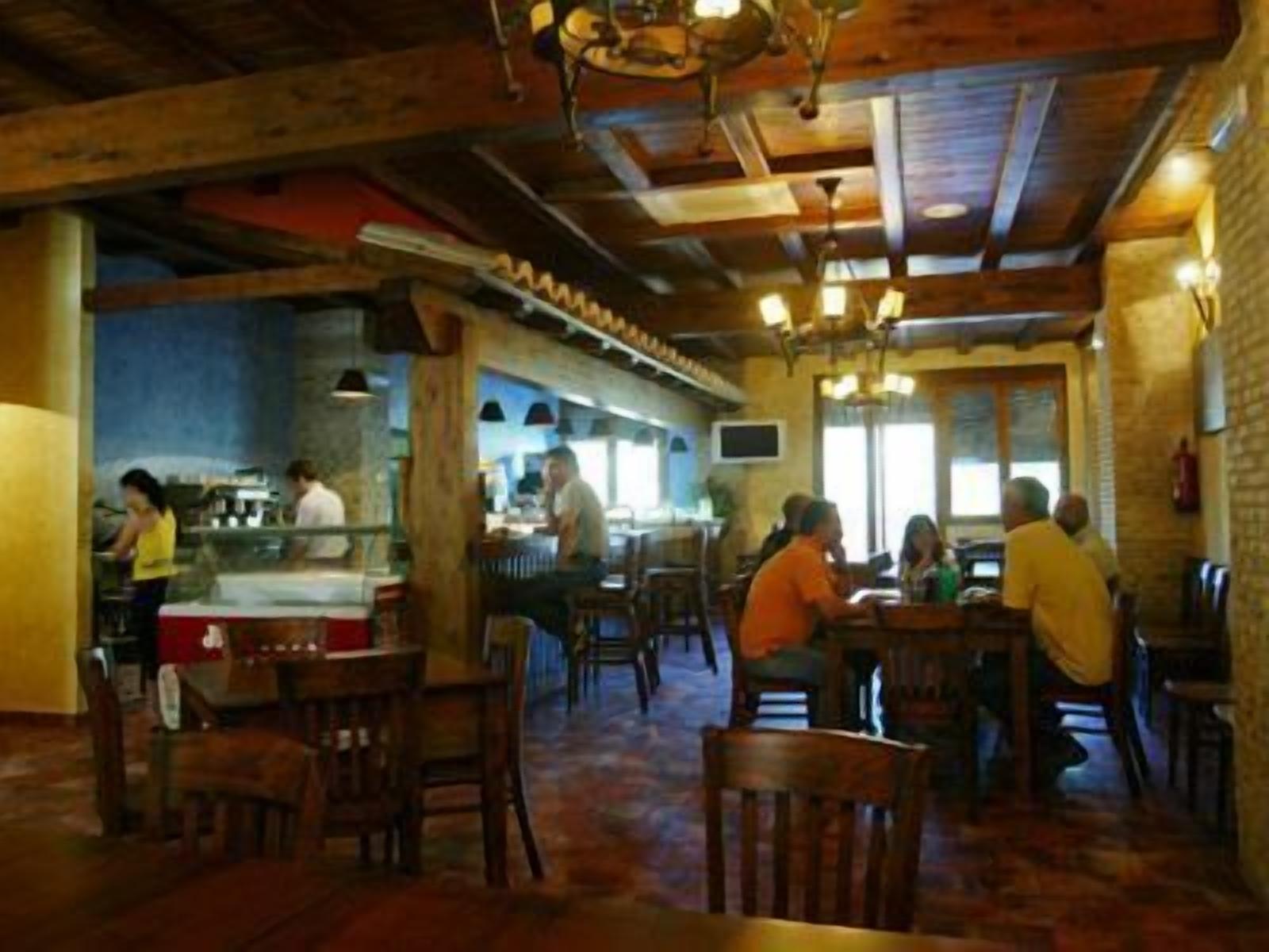 En restaurant med træbjælker og murstensvægge, med borde og stole til spisning.