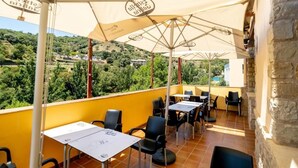 Una terraza con mobiliario exterior, sombrillas y vistas a un paisaje verde.
