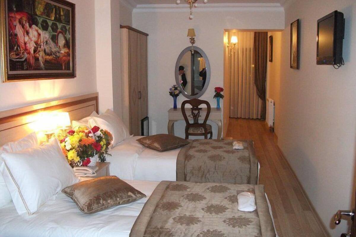 A hotel room with a bed, a chair, a desk, and a mirror.