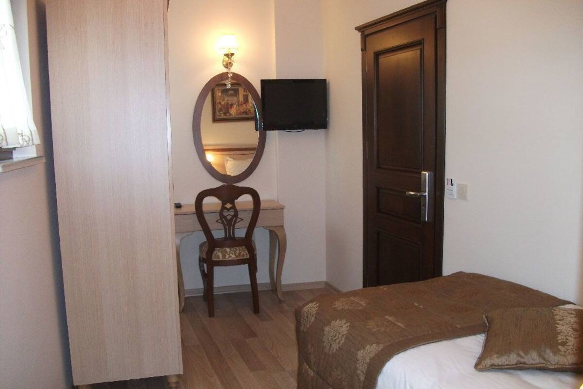 A bedroom with a bed, a desk, a chair, a television, and a wardrobe.