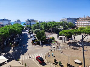A street view with parked cars, trees, and buildings.