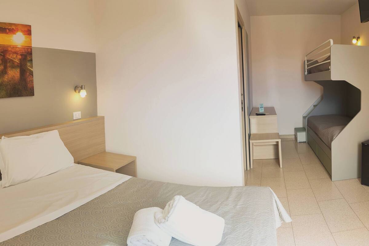 A hotel room with a bed, a desk, a chair, a sofa, and a staircase.