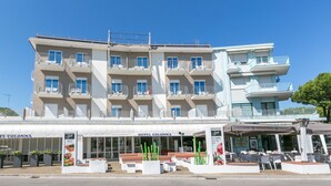 A hotel with multiple balconies, outdoor seating, and a sign for 'Hotel Colonna'. - Hotel Colonna (Jesolo)