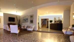 A spacious lobby with a seating area, a reception desk, and a staircase leading to another floor. - Hotel Colonna (Jesolo)