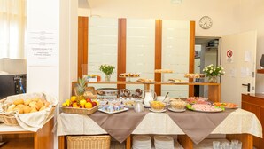 A buffet setup with various food items and beverages, a clock on the wall, and a no-smoking sign. - Hotel Colonna (Jesolo)