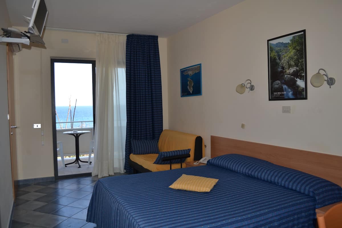 Habitación de hotel con cama, una silla, una mesa y vista al mar.