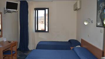 A hotel room with two beds, a desk, a television, and a window with curtains.