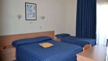 A hotel room with two beds, a wooden headboard, a desk, and a framed picture on the wall.