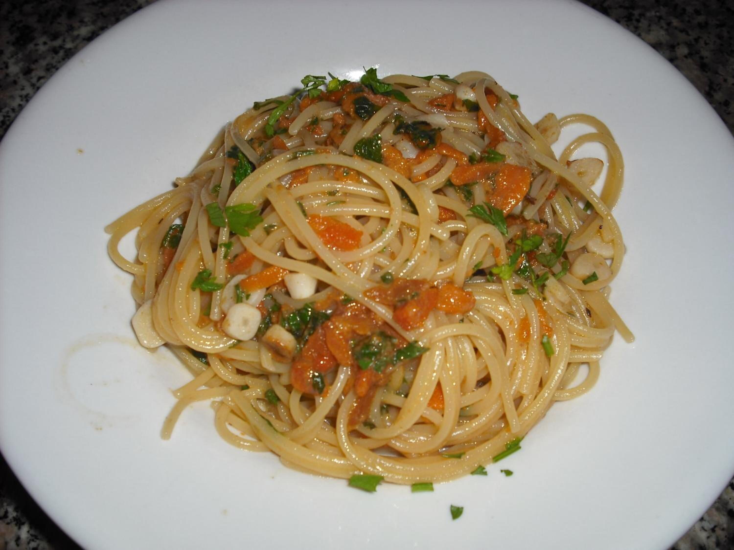Ein Teller Spaghetti mit Tomatensauce, garniert mit Kräutern.