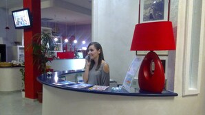 Un comptoir d’accueil avec une lampe rouge, un téléviseur fixé au mur et un tableau encadré.