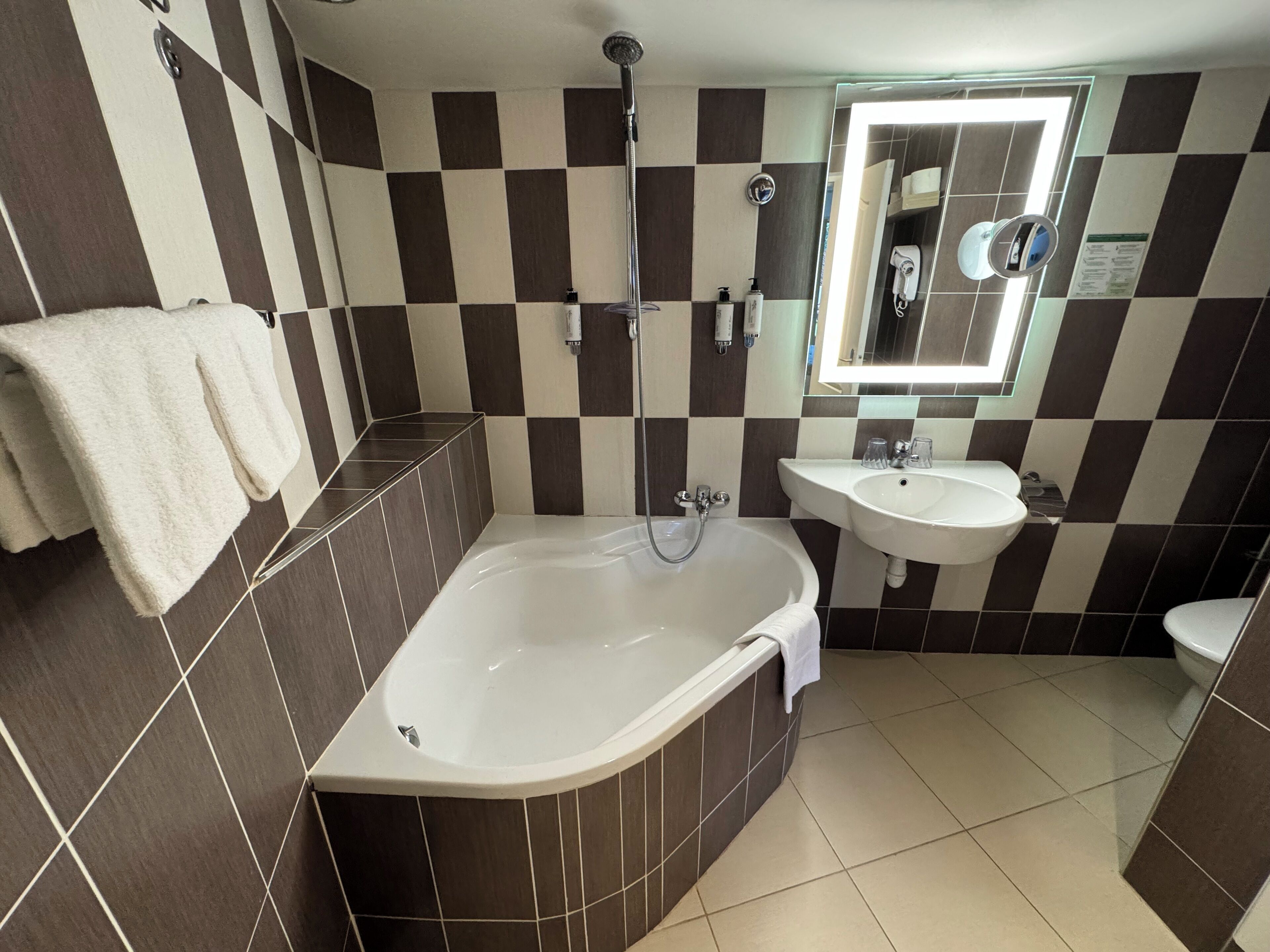 Un baño con bañera, lavamanos y espejo.