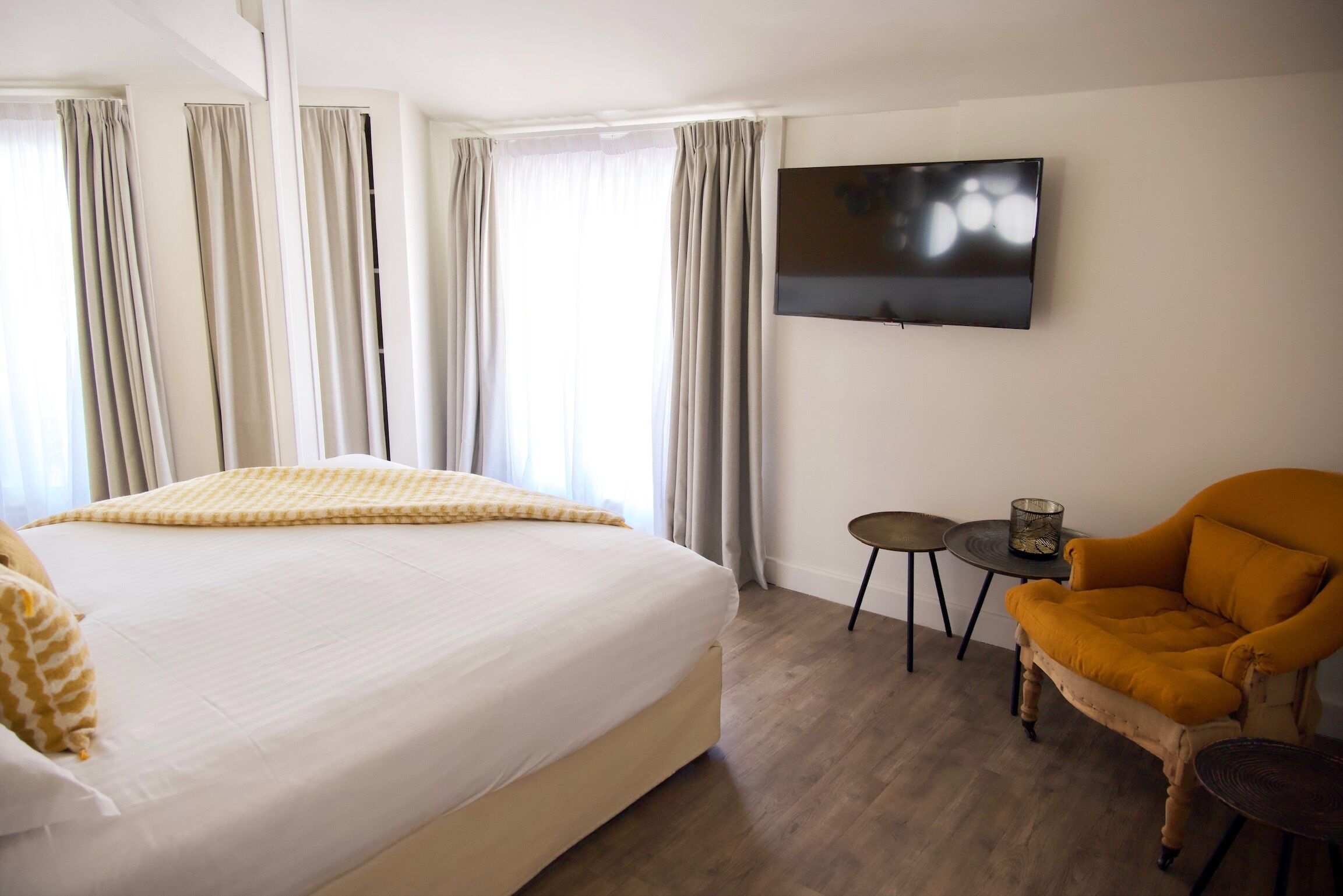 Une chambre d’hôtel avec un grand lit, un téléviseur fixé au mur, une petite table et une chaise.