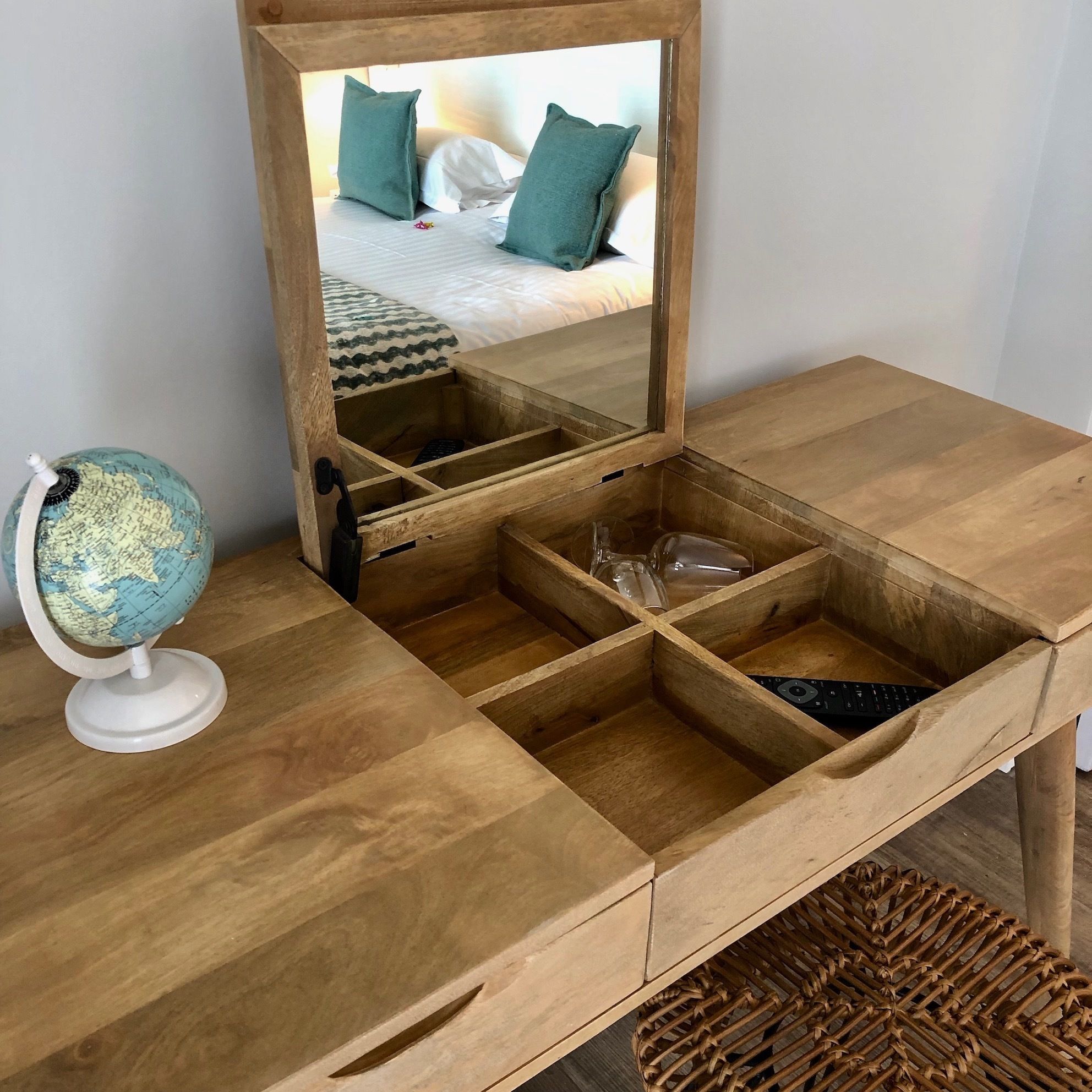 Ein Holztisch mit einem Spiegel, einem Globus und einem gewebten Korb.