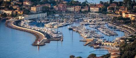 A coastal marina with numerous boats docked, surrounded by residential buildings and a prominent lighthouse.