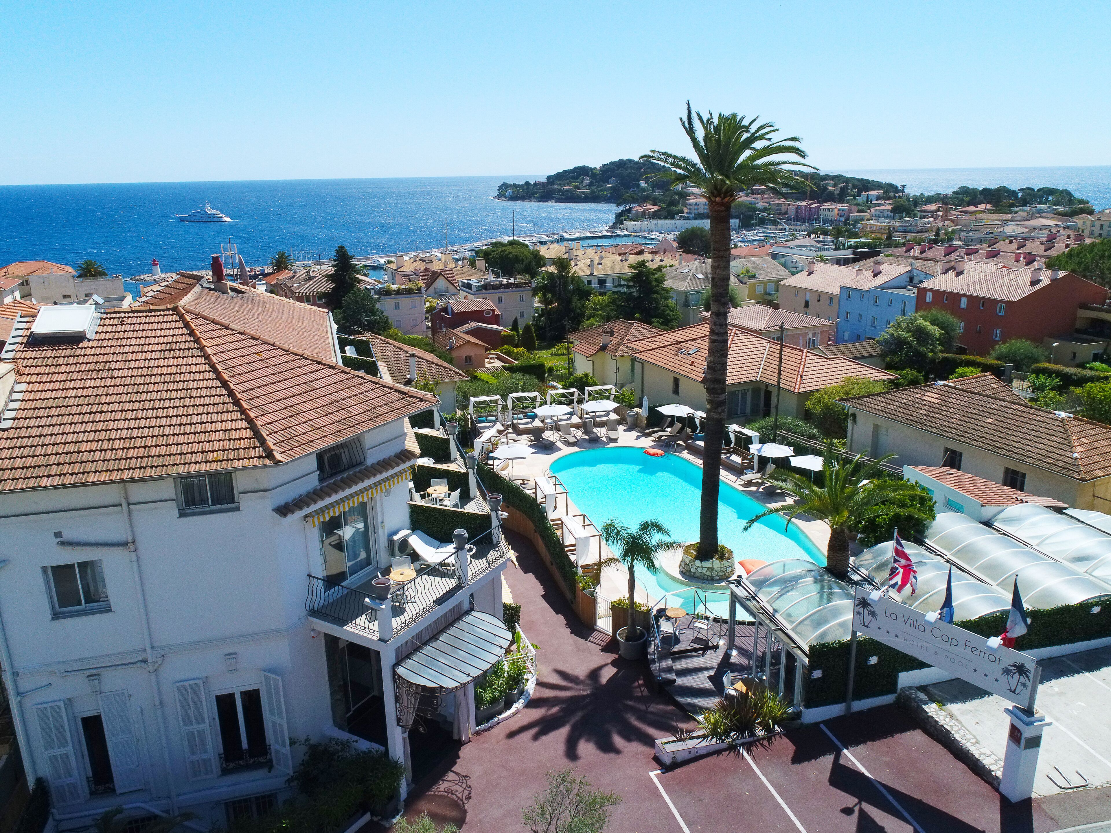 Un hotel con piscina, area salotto esterna e vista sul mare.