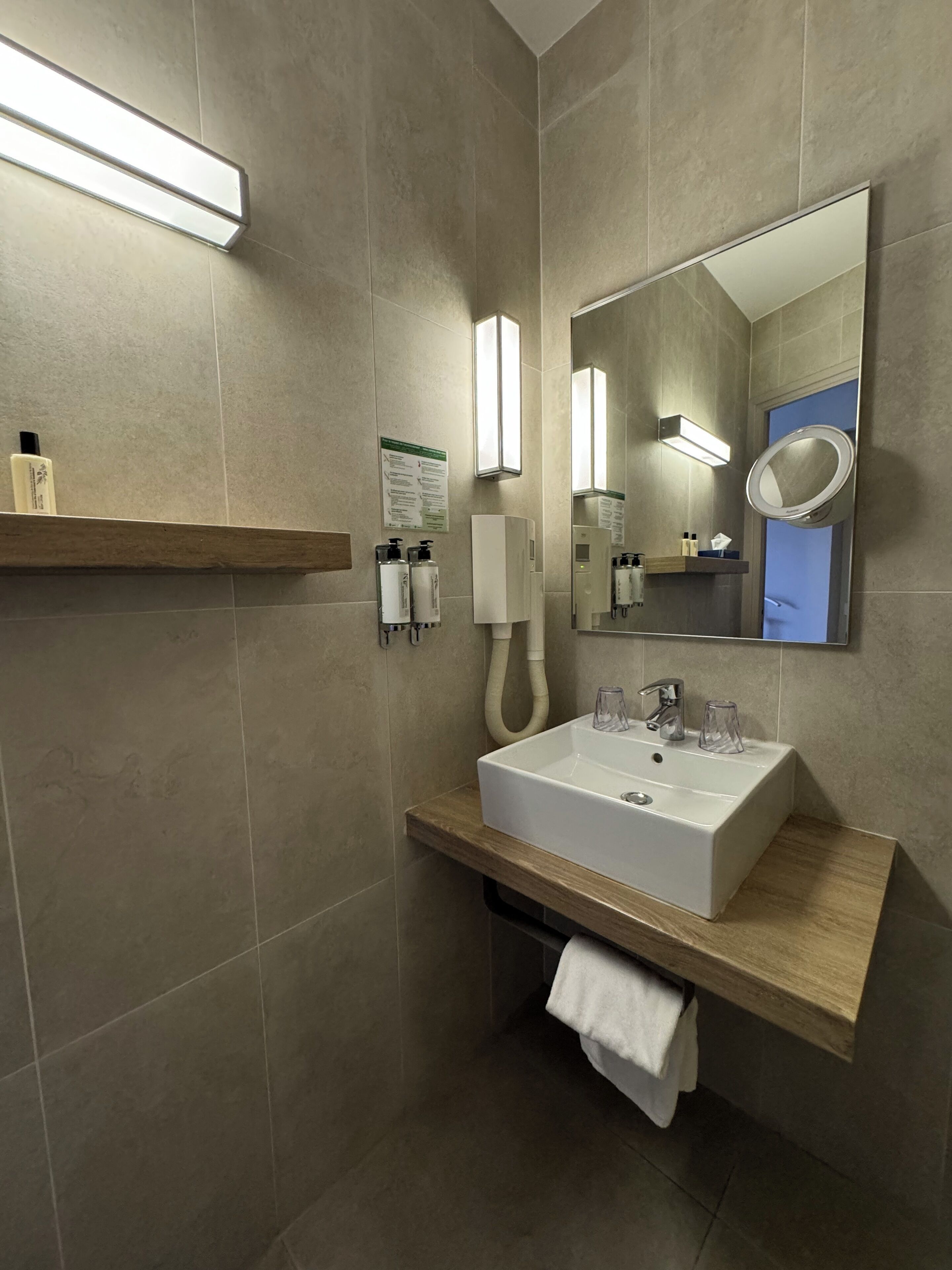 A modern bathroom with a large mirror, a sink, and a towel rack.
