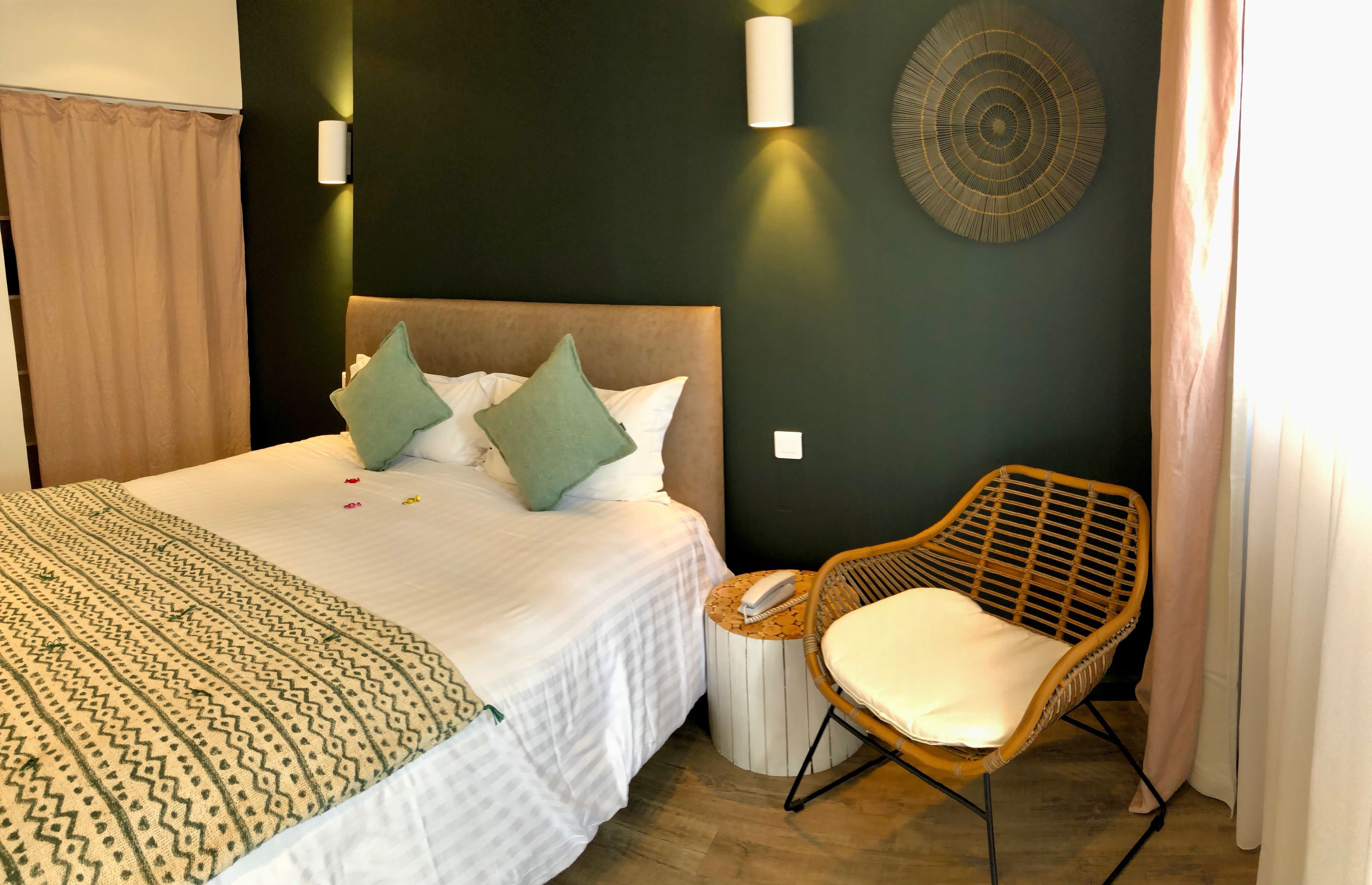A neatly made bed with a patterned blanket, two pillows, and a bedside table with a phone.